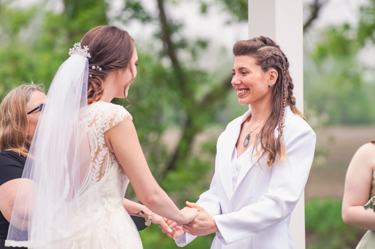 Two brides become wives to one another at a wedding ceremony at Blue Heron Barn
