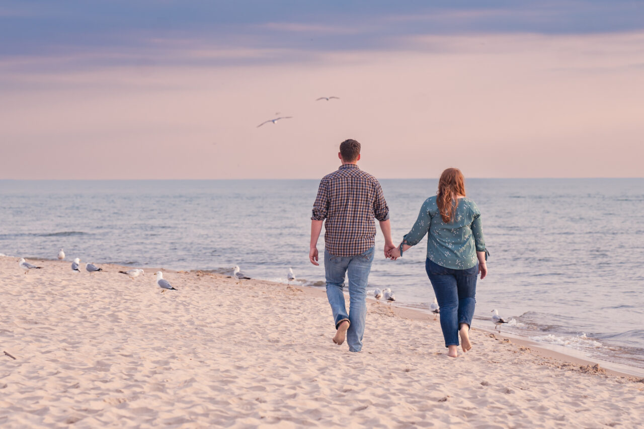 A newly engaged couple walks along the Lake Michigan Shoreline in Silver Beach at dusk