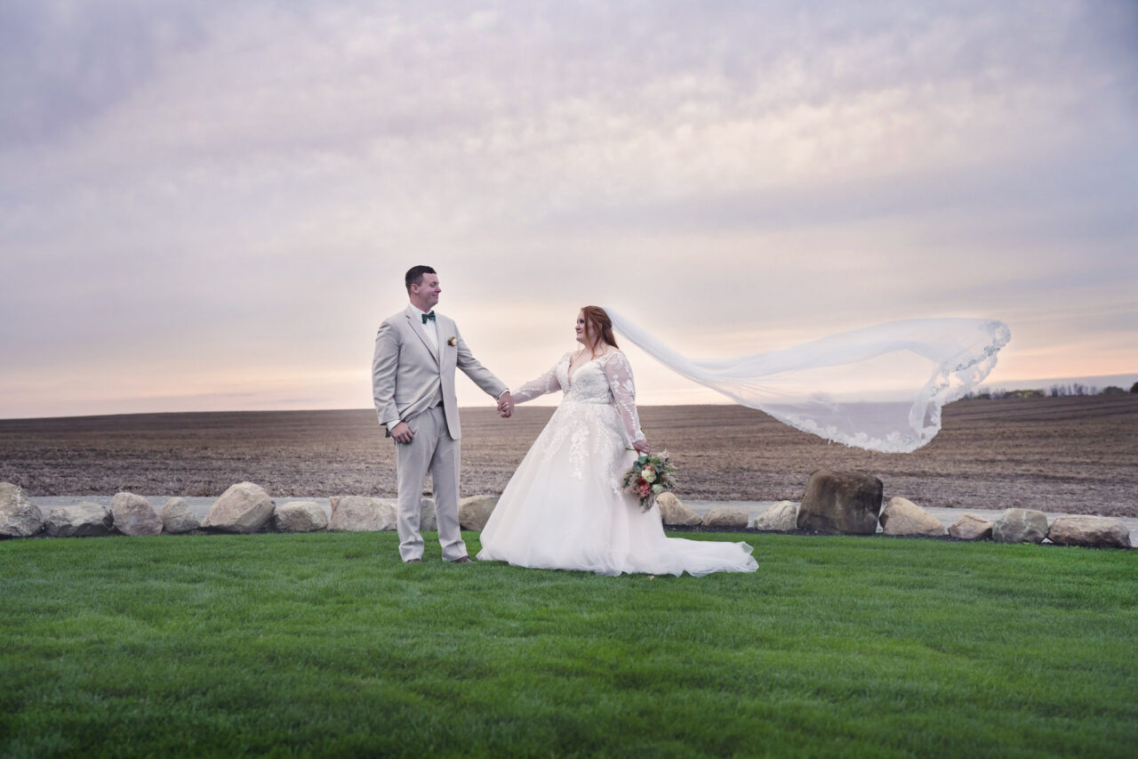 Wedding portraits - A bride and groom in an empty field with a pastel sunset sky